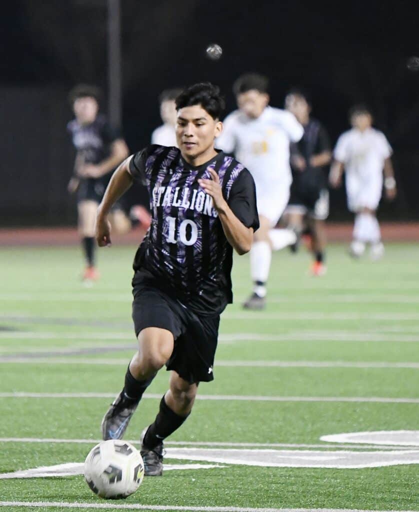 Madera Stallions soccer player dribbling during a game at night.