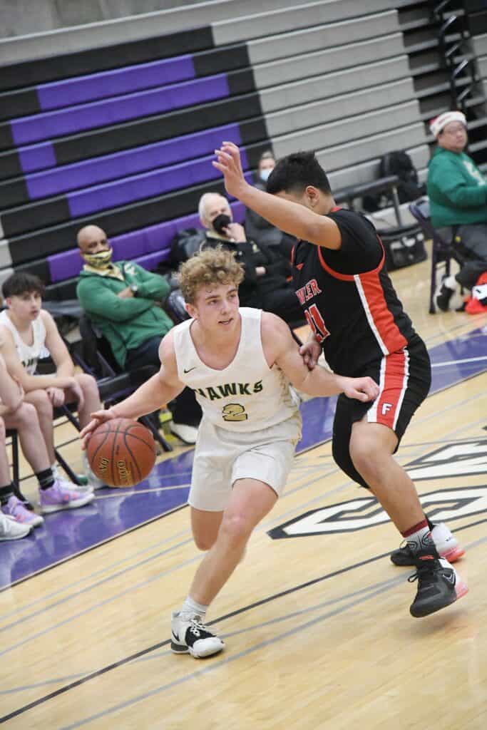 Young basketball player dribbling during a game against Hawks.