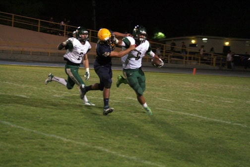 Madera Panthers running back with ball, chased by Hawks defenders during night game.