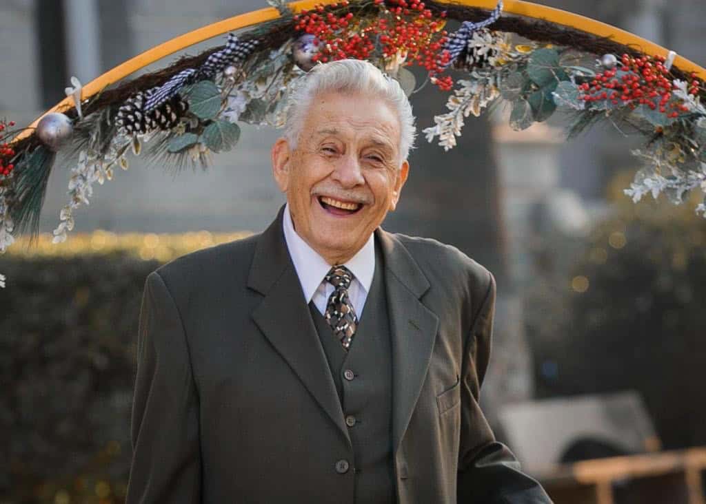 Elderly man smiling at a funeral, celebrating Salvador Figueroa Aguayo's life.