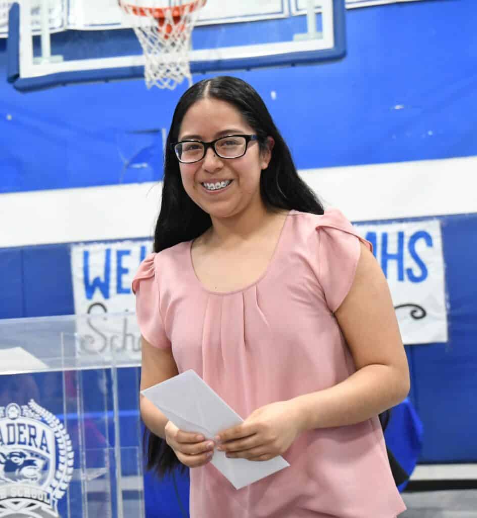 Farm worker woman smiling with diploma at graduation ceremony.