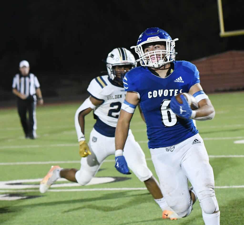 Coyotes player runs with football during a game against Bulldogs.