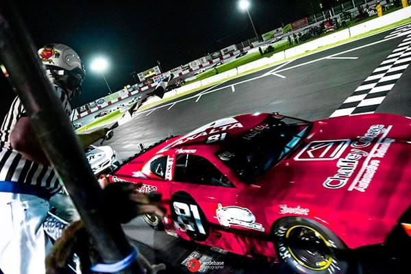 Madera Speedway race car crossing the finish line at night.