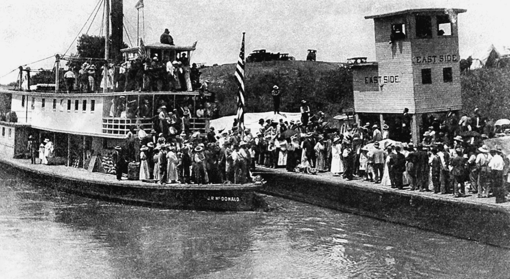 Historic steamboat docked on San Joaquin River with crowd of people.