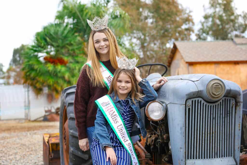 Madera queens wearing crowns and sashes pose with tractor for Central California event.