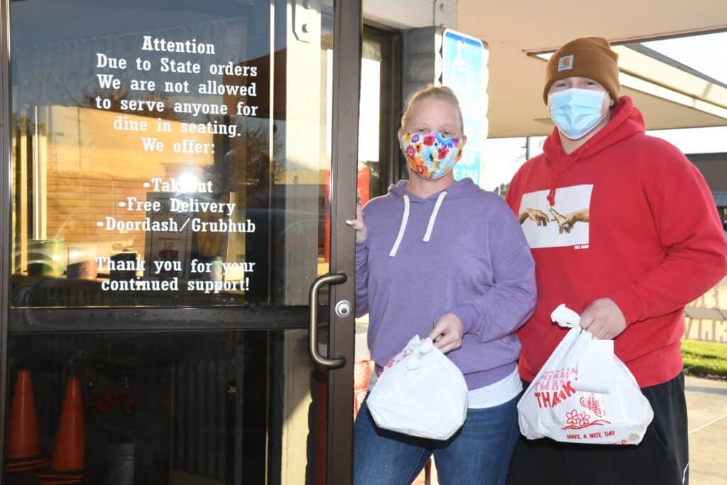 People wearing masks outside restaurant during stay-at-home order.