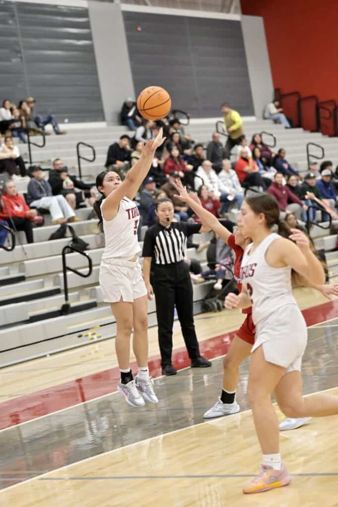 Girls basketball player shooting during game at Madera gym.